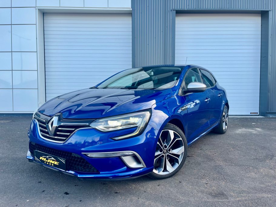 Voiture Renault Mégane iv gtline bleue stationnée devant un mur gris.